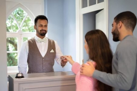 receptionist-taking-credit-card-from-couple-receiving-payment-accomodation_116547-56026